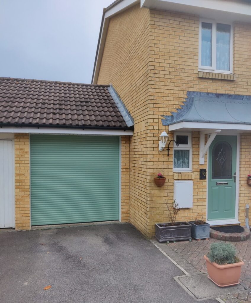 Roller garage door in chartwell green, installed to match the existing front door of the house.
